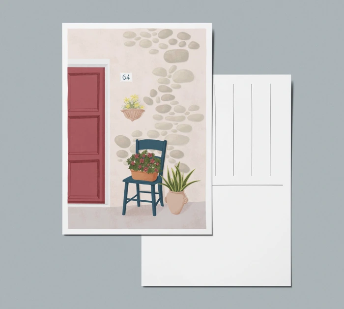 Mockup fronte e retro di una cartolina illustrata con una sedia di fronte a una porta rossa e vasi su muro di pietra di un villaggio mediterraneo.