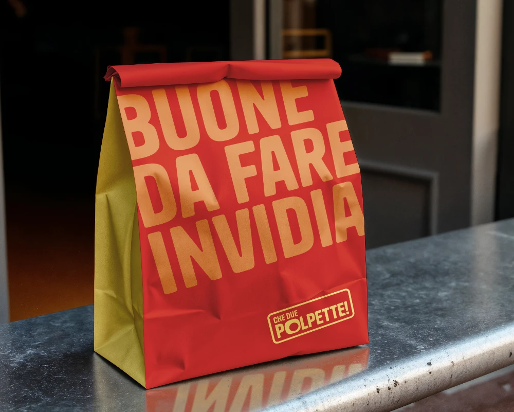 Mockup di un sacchetto d'asporto in carta, che mette in mostra il tono di voce irriverente e il logo del brand con il claim "buone da fare invidia".